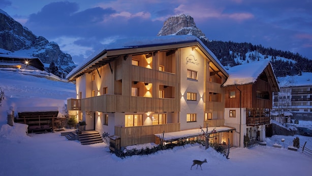 A multi-story wooden building with a balcony, surrounded by snow-covered landscape and mountains. - Residence Settsass (Corvara in Badia)