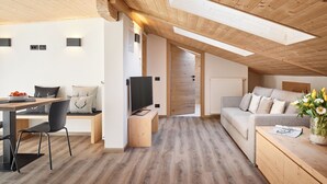 A modern loft bedroom with a wooden ceiling, a built-in desk, a sofa, and a TV. - Residence Settsass (Corvara in Badia)