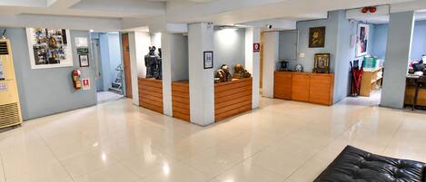 A hotel lobby with a reception desk, a black leather couch, and a fire extinguisher on the wall.