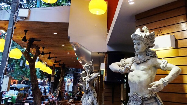 A restaurant with wooden ceiling and yellow hanging lights, a statue, and outdoor seating. - Villa Cha-Cha Khaosan-Rambuttri (Bangkok)