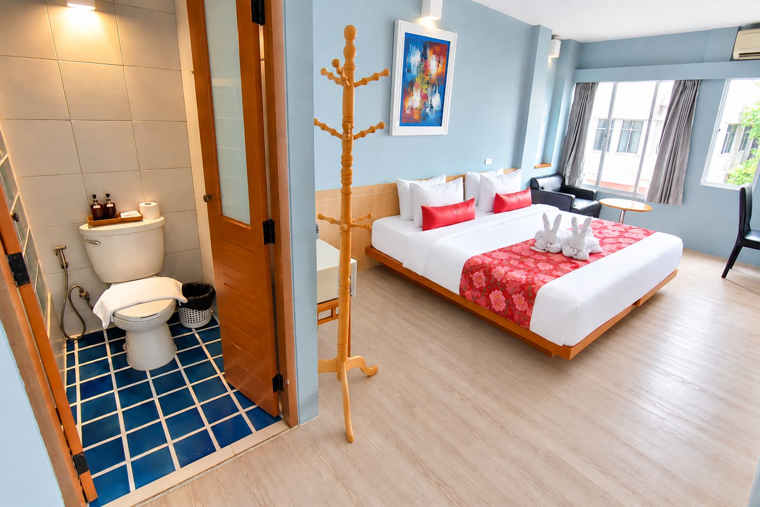 Ein Hotelzimmer mit Bett, Schreibtisch, Stuhl, Fenster und Bad.