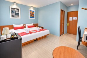 Une chambre d’hôtel avec un lit, des tables de chevet, un bureau et une chaise.