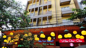 A building with balconies, a neon sign for a seafood restaurant, and hanging yellow lights. - Villa Cha-Cha Khaosan-Rambuttri (Bangkok)