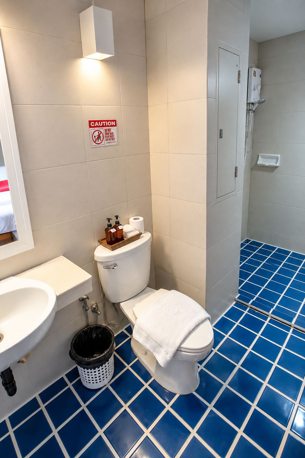 A bathroom with a toilet, sink, and a caution sign on the wall.
