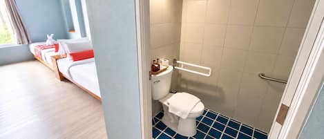 A hotel room with a bed, a bathroom with a toilet and a shower, and a view of the outdoors.