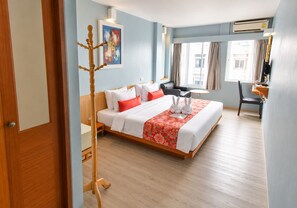 A hotel room with a bed, a desk, a chair, a window with curtains, and an air conditioning unit. - Villa Cha-Cha Khaosan-Rambuttri (Bangkok)