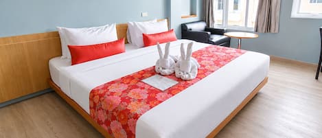 A hotel room with a bed, pillows, a small table, and a chair.