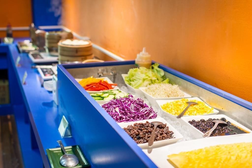 A buffet with various food items including vegetables, rice, and beans.