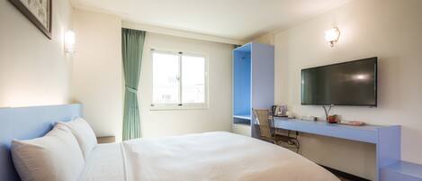 A hotel room with a bed, a desk, a chair, a television, and a window with curtains.