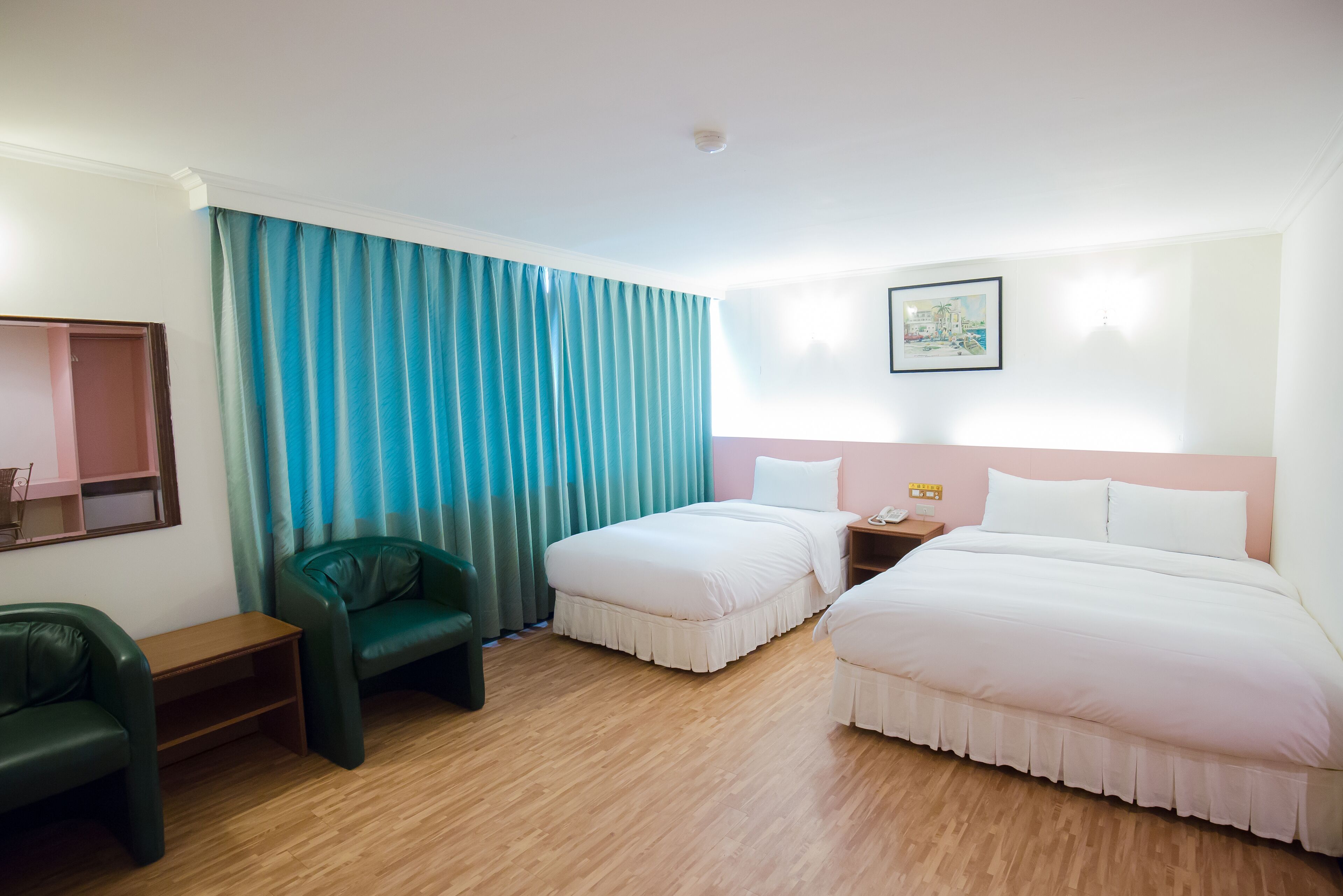 A hotel room with two beds, a desk, a chair, and a window with curtains.