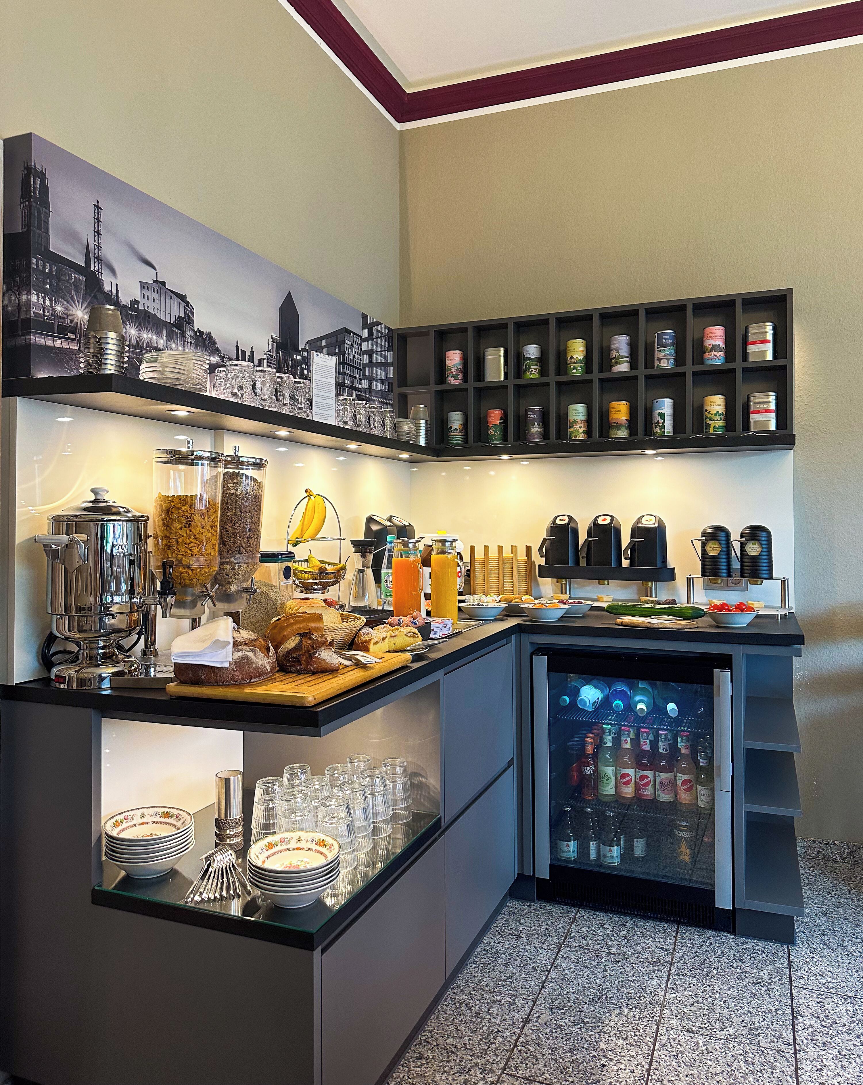 A modern breakfast bar with a coffee machine, fruit, and a beverage cooler.