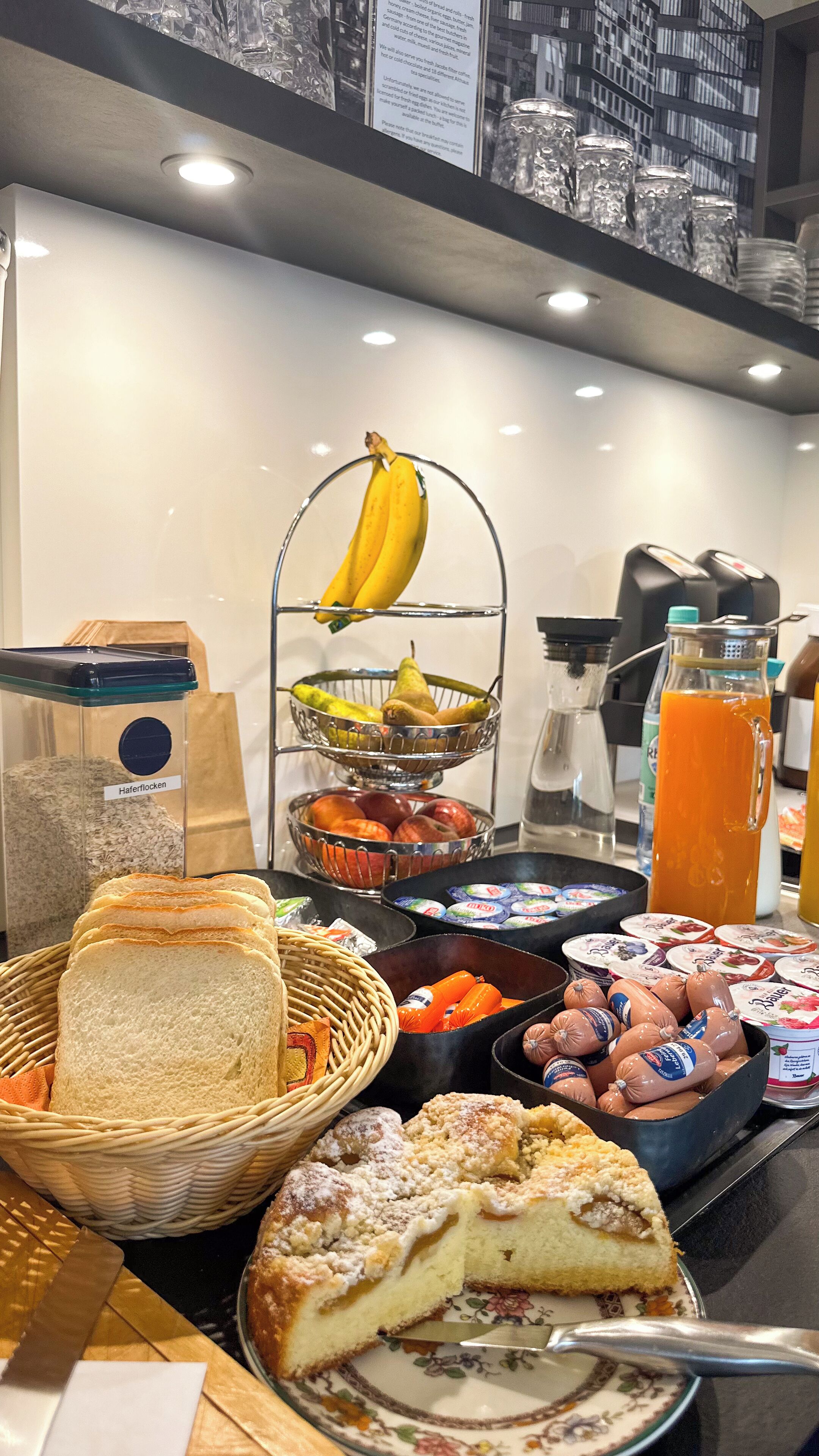 Un bufé de desayuno con pan, bollería, frutas y bebidas.