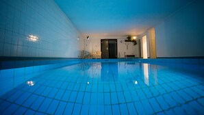 En indendørs swimmingpool med fliserede vægge og udsigt til himlen.