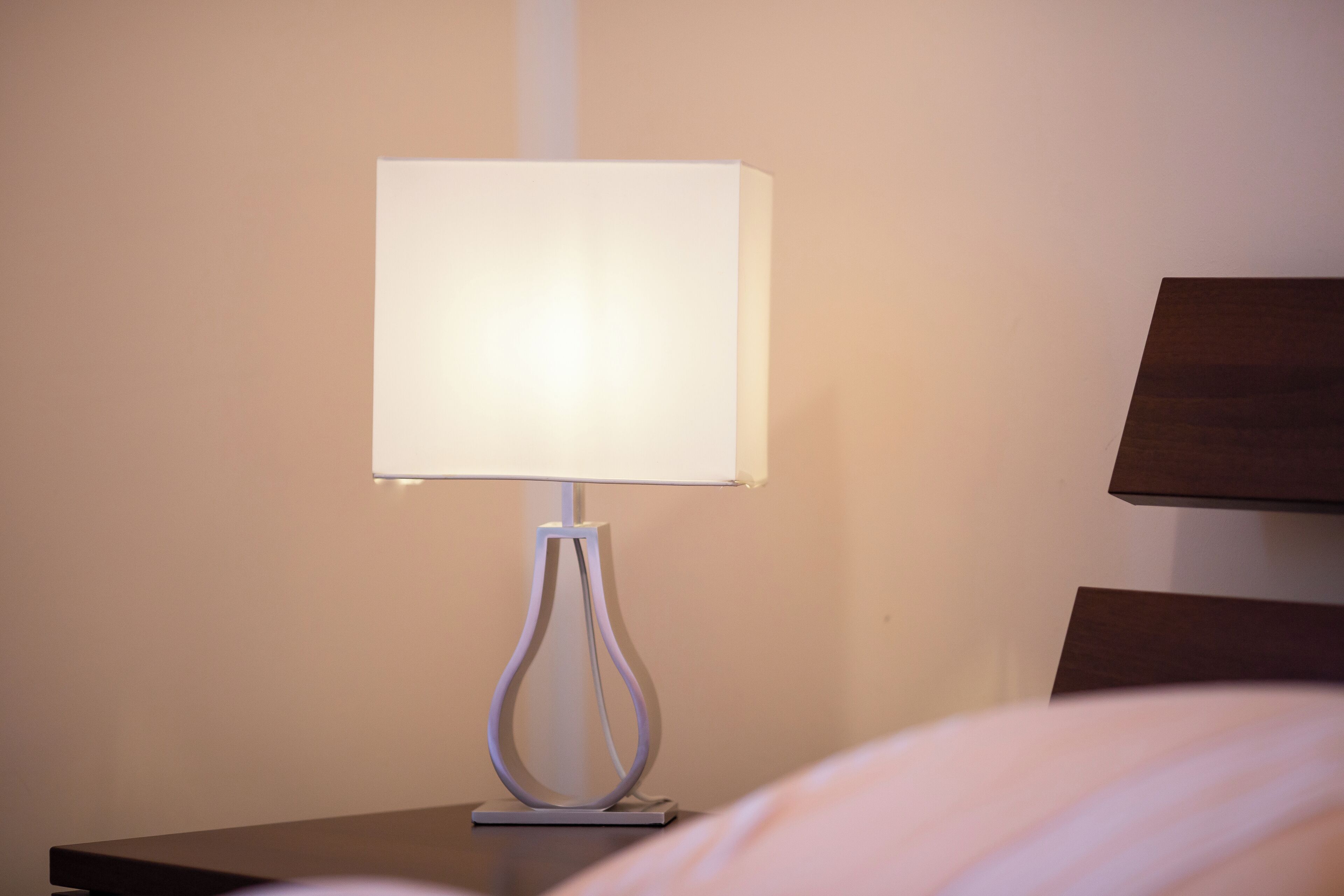 Une table de chevet avec une lampe moderne et une tête de lit en bois.