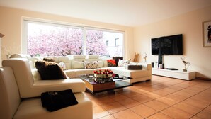 En moderne stue med sofa, sofabord og et tv ophængt på væggen.