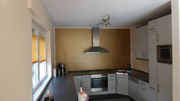 A modern kitchen with a built-in oven, stainless steel cabinets, and a window with blinds.