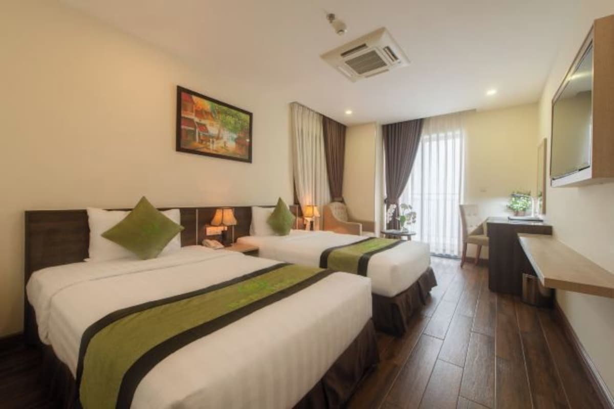 A hotel room with two beds, a desk, a chair, and a large window with curtains.