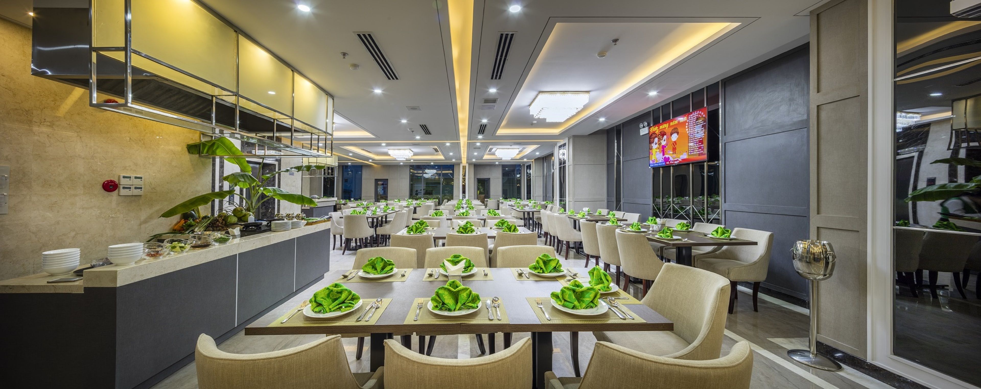 A modern restaurant with multiple dining tables, each set with green napkins and silverware.