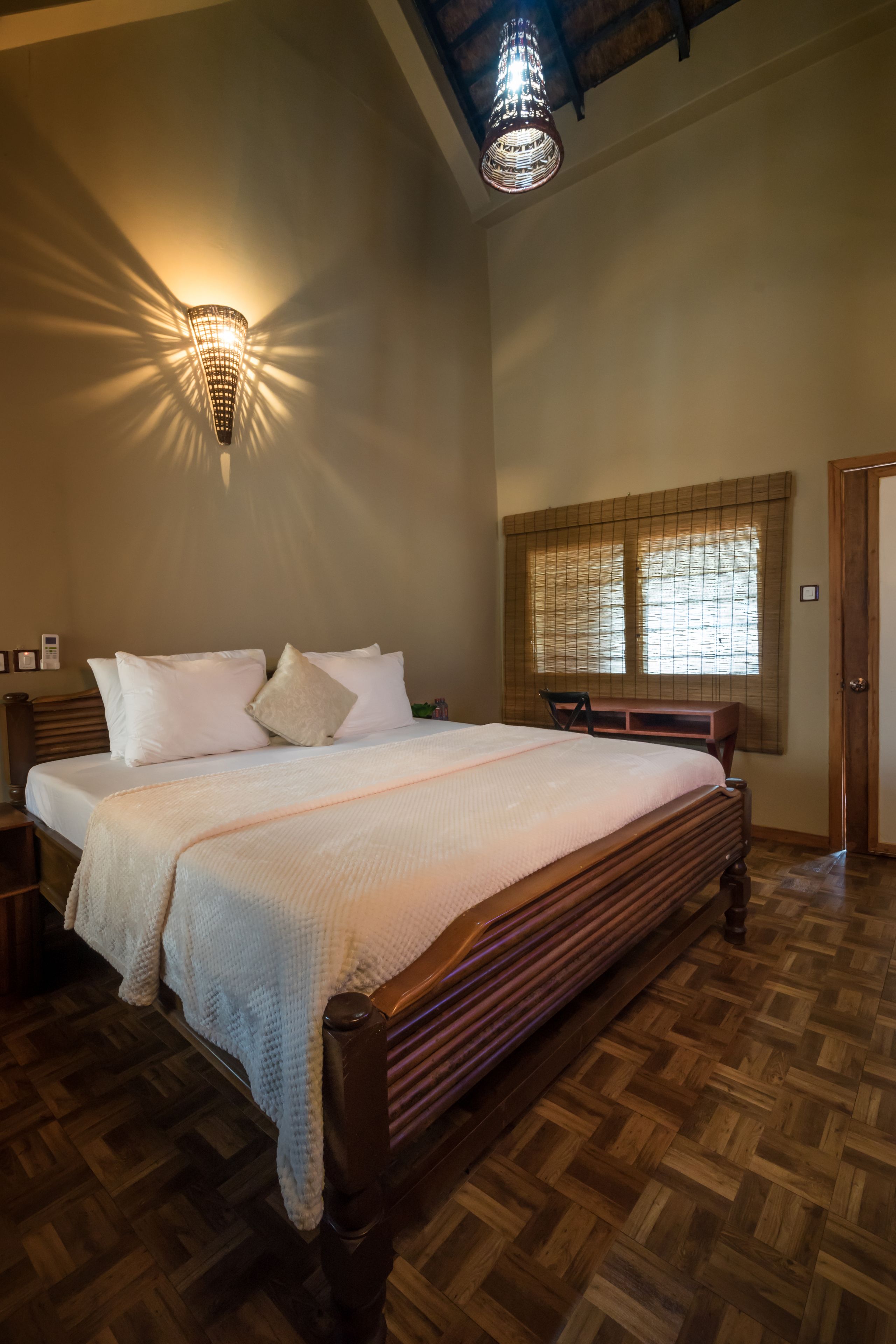 Una camera da letto con un letto grande, una testiera in legno, una panca ai piedi del letto, una finestra con persiane e una porta.