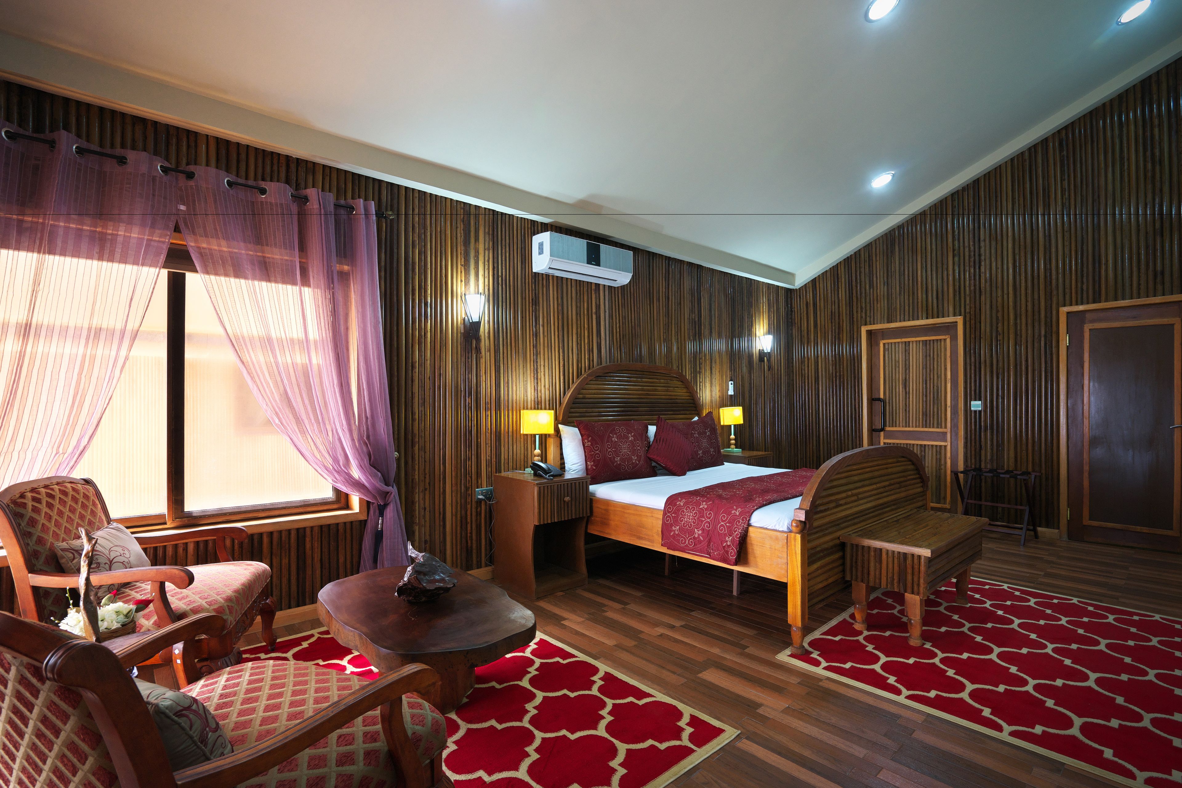 A hotel room with a bed, a chair, a table, and a window with curtains.