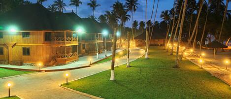 A resort with wooden buildings, palm trees, and a paved walkway.