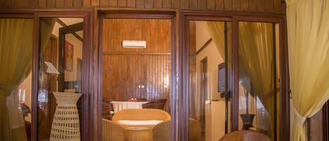 A wooden-paneled room with wicker furniture, a small table, and a chair.