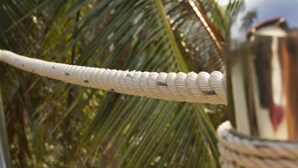 A close-up of a woven rope railing with a metallic structure in the background. - Karo Villas (Koh Tao)