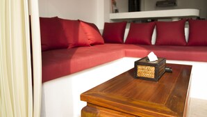 A modern living room with a red sectional sofa, a wooden coffee table, and a white wall. - Karo Villas (Koh Tao)