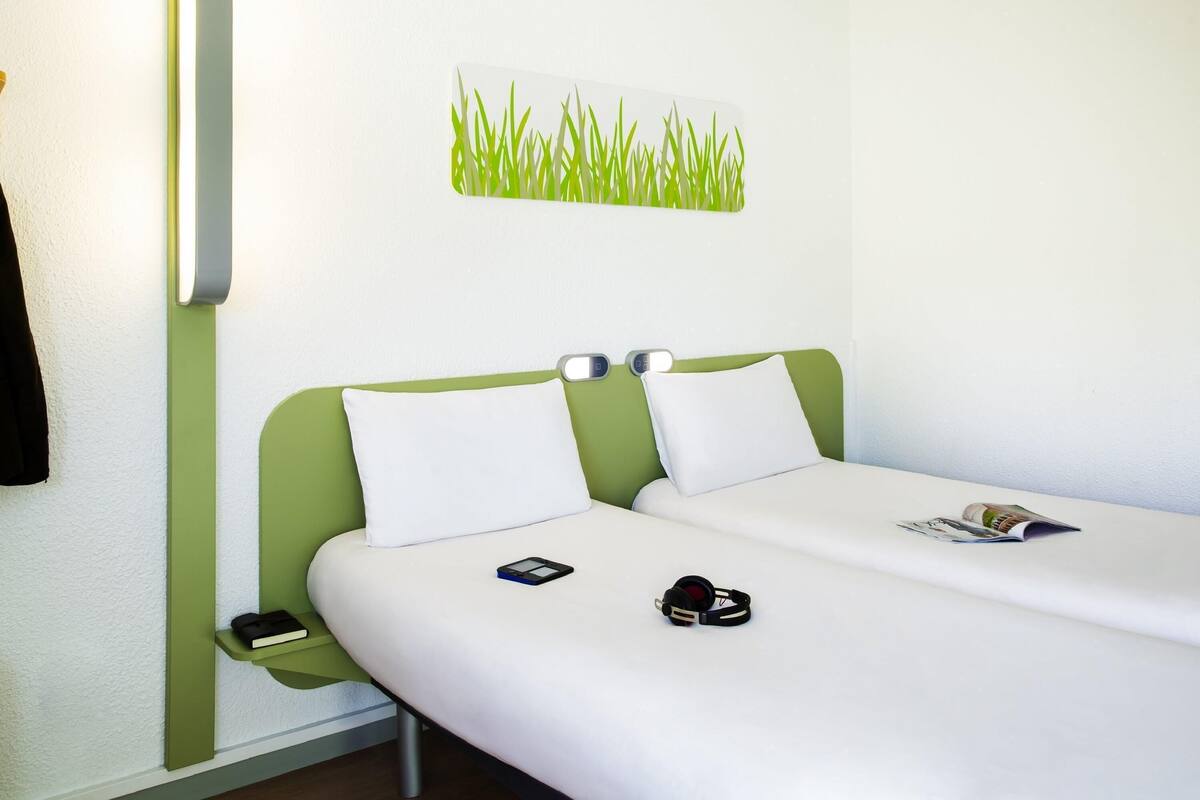 Een hotelkamer met een bed, nachtkastjes, een aan de muur bevestigde telefoon en een kunstwerk.