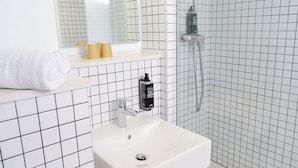 A bathroom with a white sink, a mirror, a towel, and a shower area. - ibis budget Toulouse Colomiers (Colomiers)
