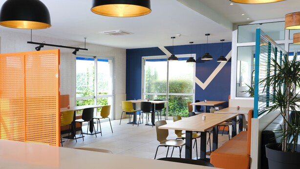 A modern dining area with high tables, chairs, and pendant lighting. - ibis budget Toulouse Colomiers (Colomiers)