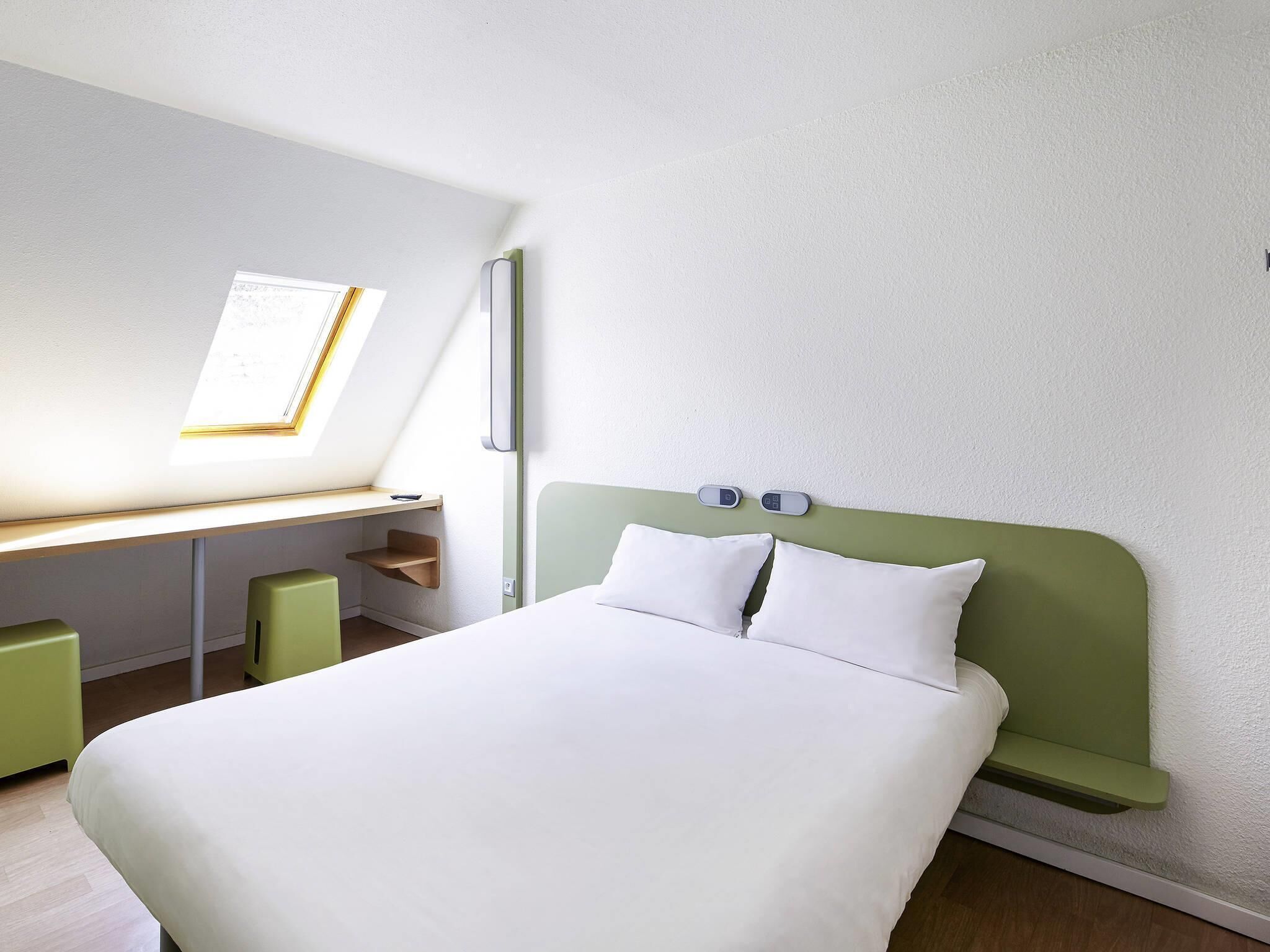Una habitación de hotel con cama, escritorio y ventana.