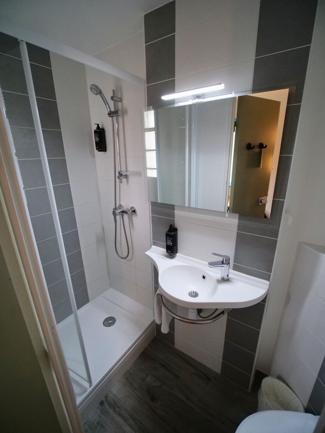 A modern bathroom with a shower, a sink, and a toilet.