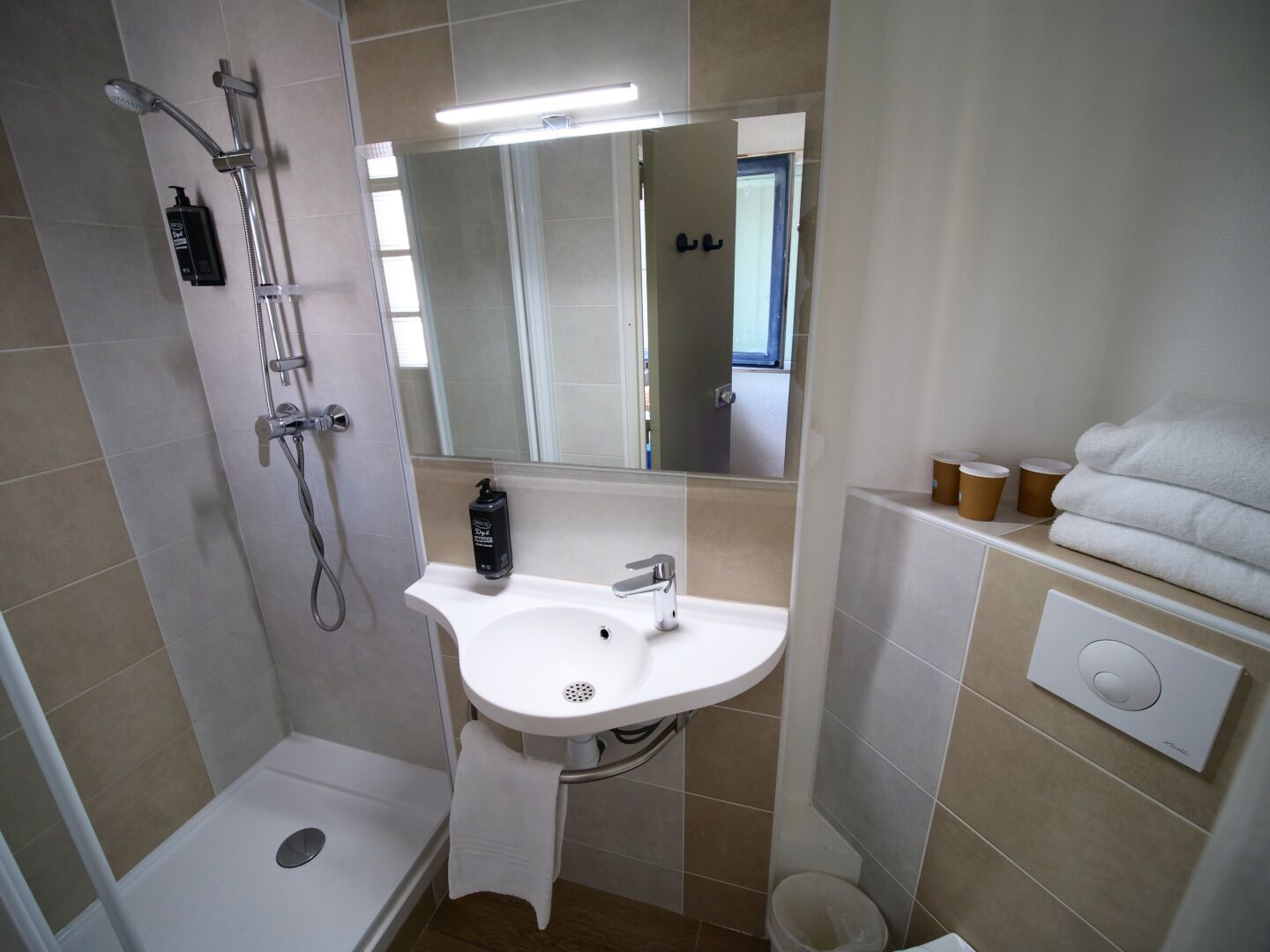 A bathroom with a shower, sink, mirror, and towel rack.