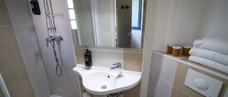 A bathroom with a shower, sink, mirror, and towel rack.