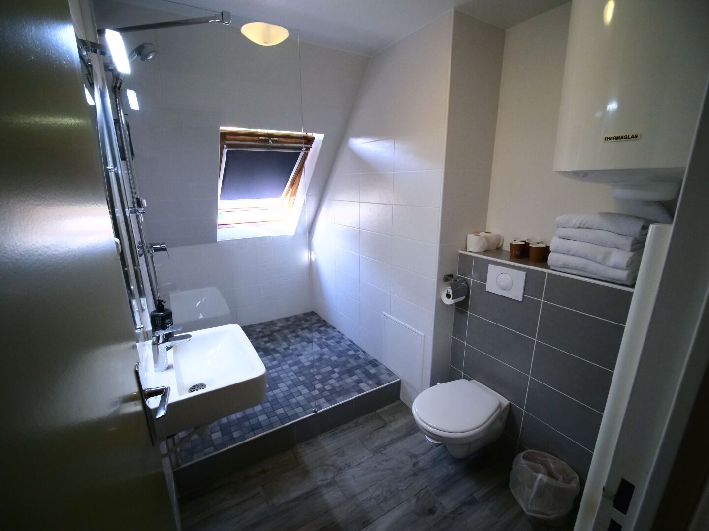 Et lille badeværelse med bruser, toilet og håndvask.