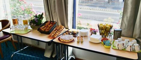 A breakfast buffet table with various pastries, a pitcher, and a bowl of flowers.