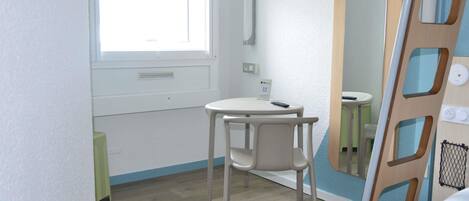 A small, well-lit room with a single white chair, a small table, and a window.