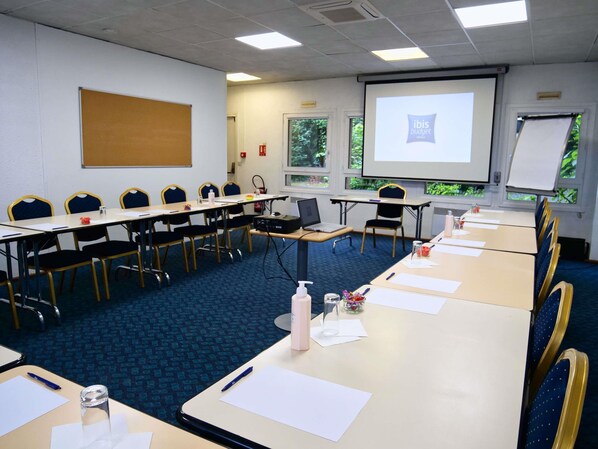 A conference room with a long table, chairs, a projector screen, and a whiteboard.