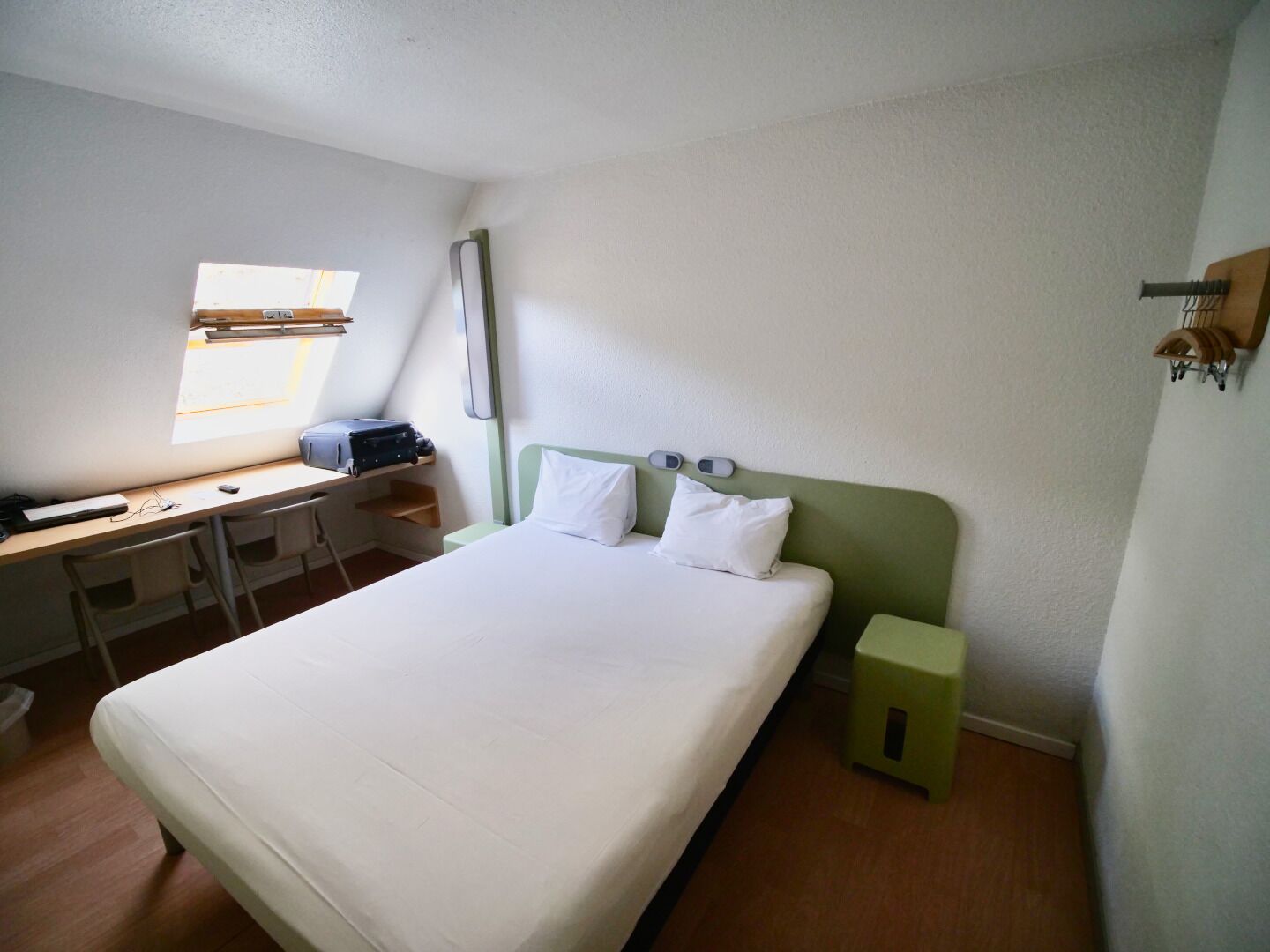 Una habitación pequeña y limpia con cama, escritorio y ventana.