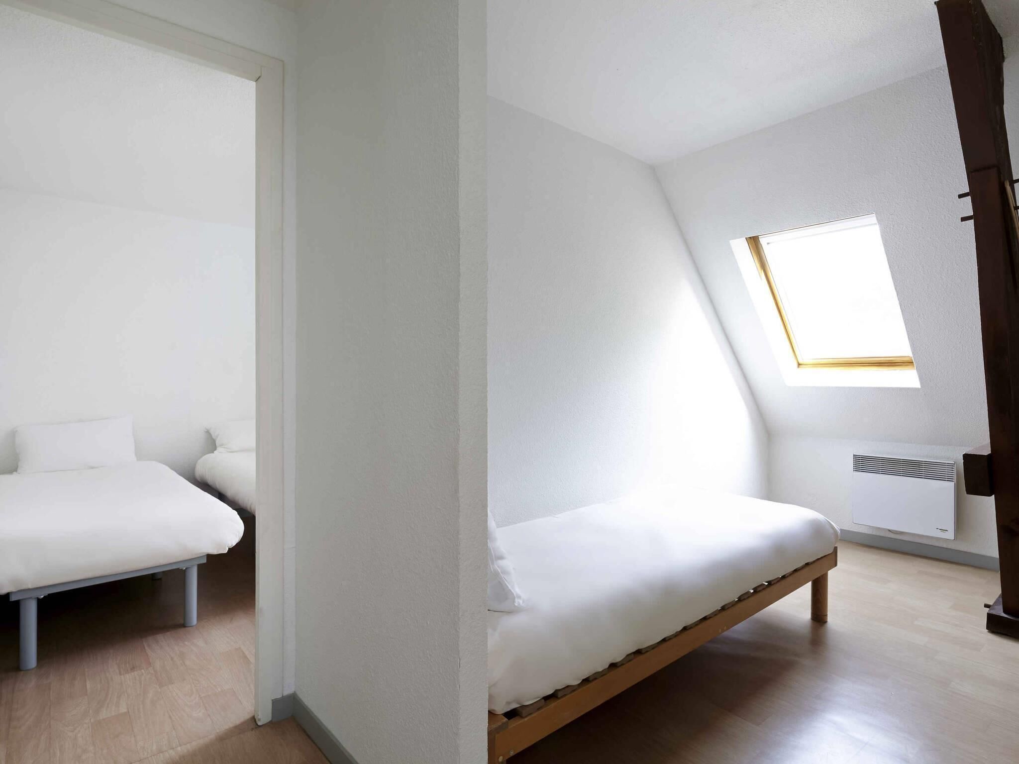 Una habitación con dos camas, un tragaluz y un radiador.