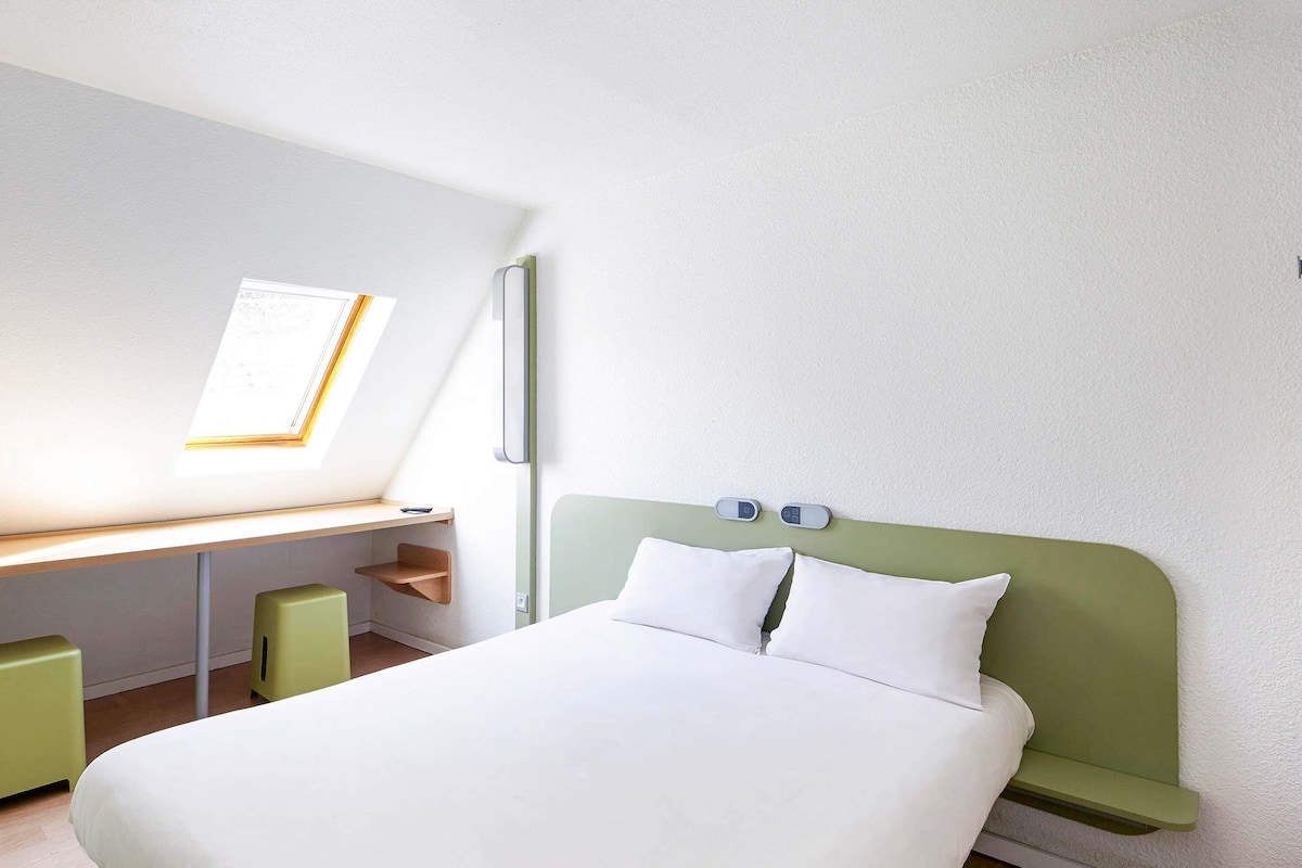 Ein Schlafzimmer mit einem Bett, einem Schreibtisch und einem Fenster.