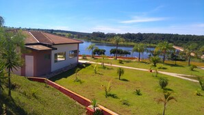 Una casa con tetto in tegole, un prato con alberi e uno specchio d'acqua sullo sfondo.