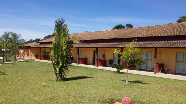 A building with a tiled roof and a covered outdoor area with chairs. - CANTO VERDE HOTEL PARA RANCHARIA PARK HOTEL (Rancharia)
