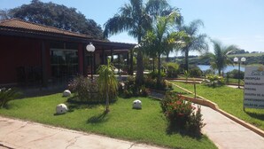 Un hotel con un edificio rosso, una piscina e un cartello che elenca servizi come ristorante e palestra.