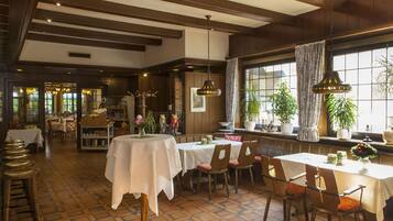 Ein Restaurant mit Holzeinrichtung, weißen Tischdecken und Zimmerpflanzen.