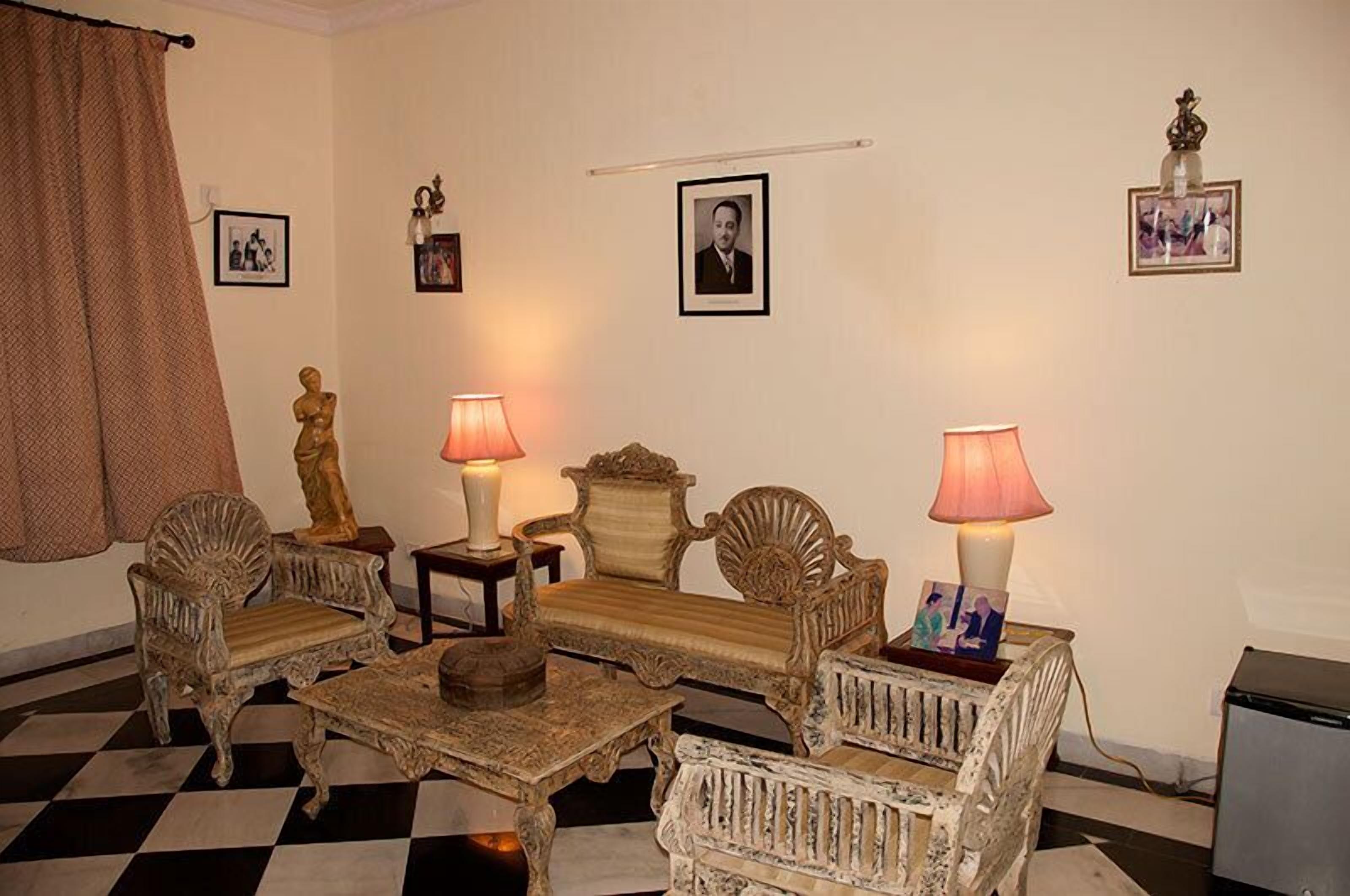 A room with antique furniture, including a sofa, chairs, and a coffee table. There are two lamps on side tables, and the room has a checkered floor.