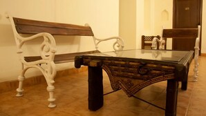 Una habitación con una mesa de vidrio, dos sillas blancas y un banco de madera.