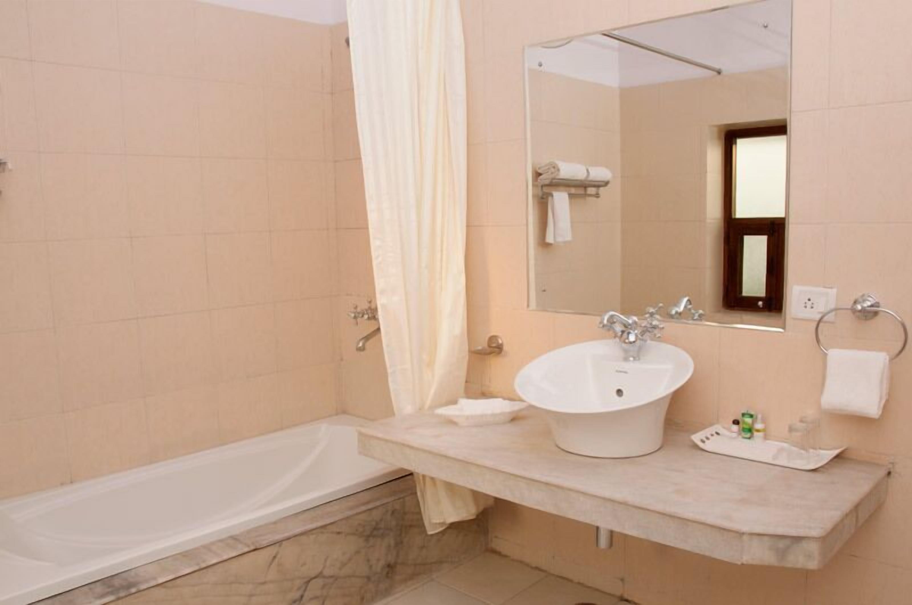 Un baño con bañera, lavabo, espejo y perchero para toallas.