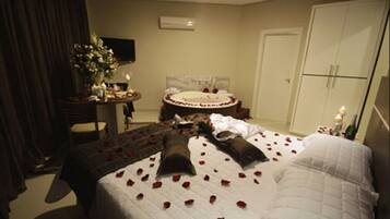Habitación de hotel con cama, escritorio, silla, televisor y armario.